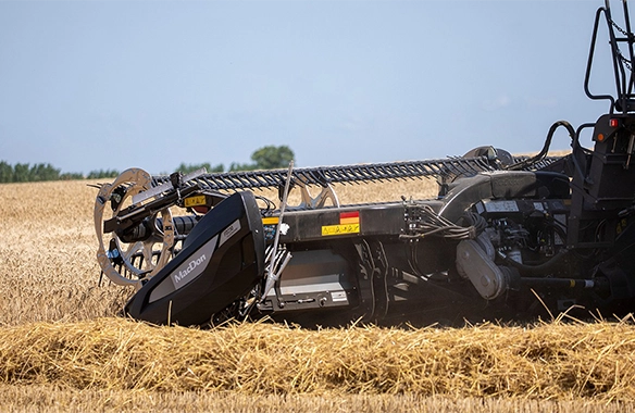 Side profile of MacDon draper header cutting through golden wheat, delivering clean and uniform crop flow to the combine.