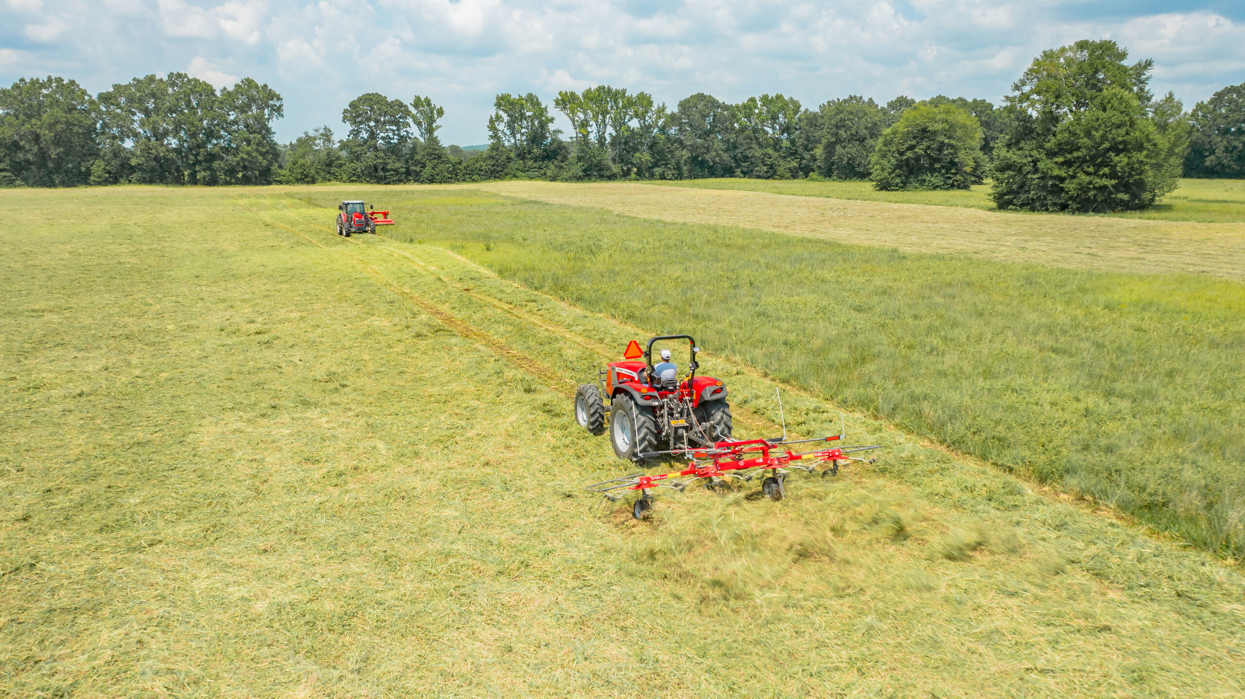 Massey Ferguson 4700 and 5700 Series tractors working in tandem with disc mower and tedder for efficient hay harvesting in open field.