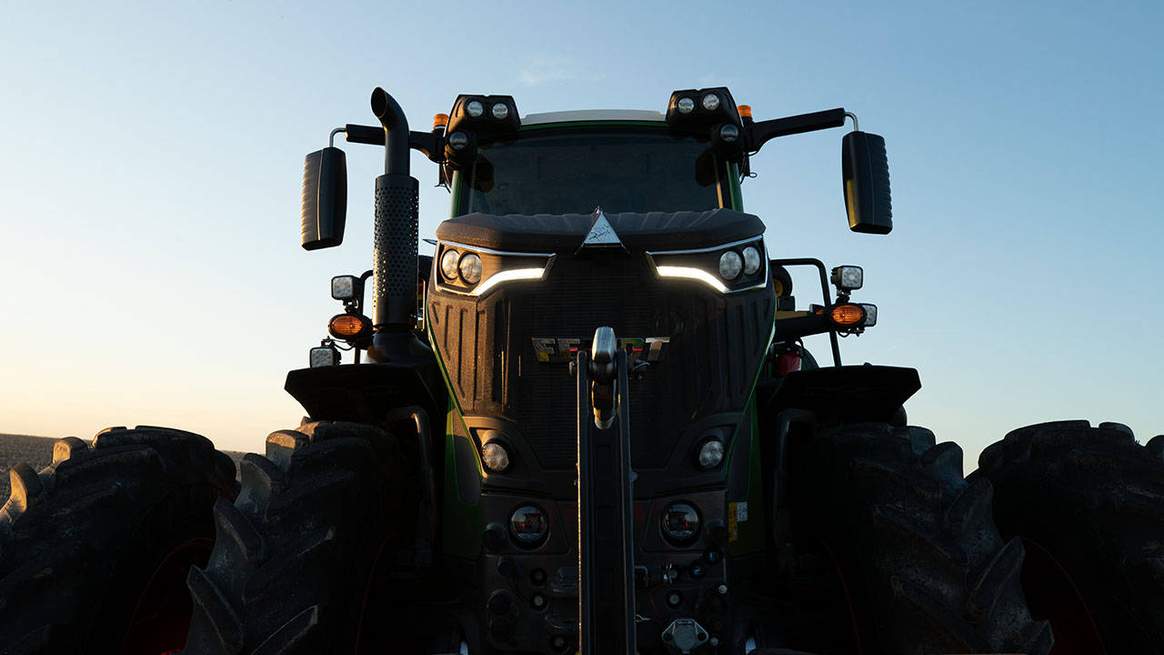 Front view of Fendt 1000 Vario tractor at sunrise, showcasing LED headlights and rugged design for powerful field performance.