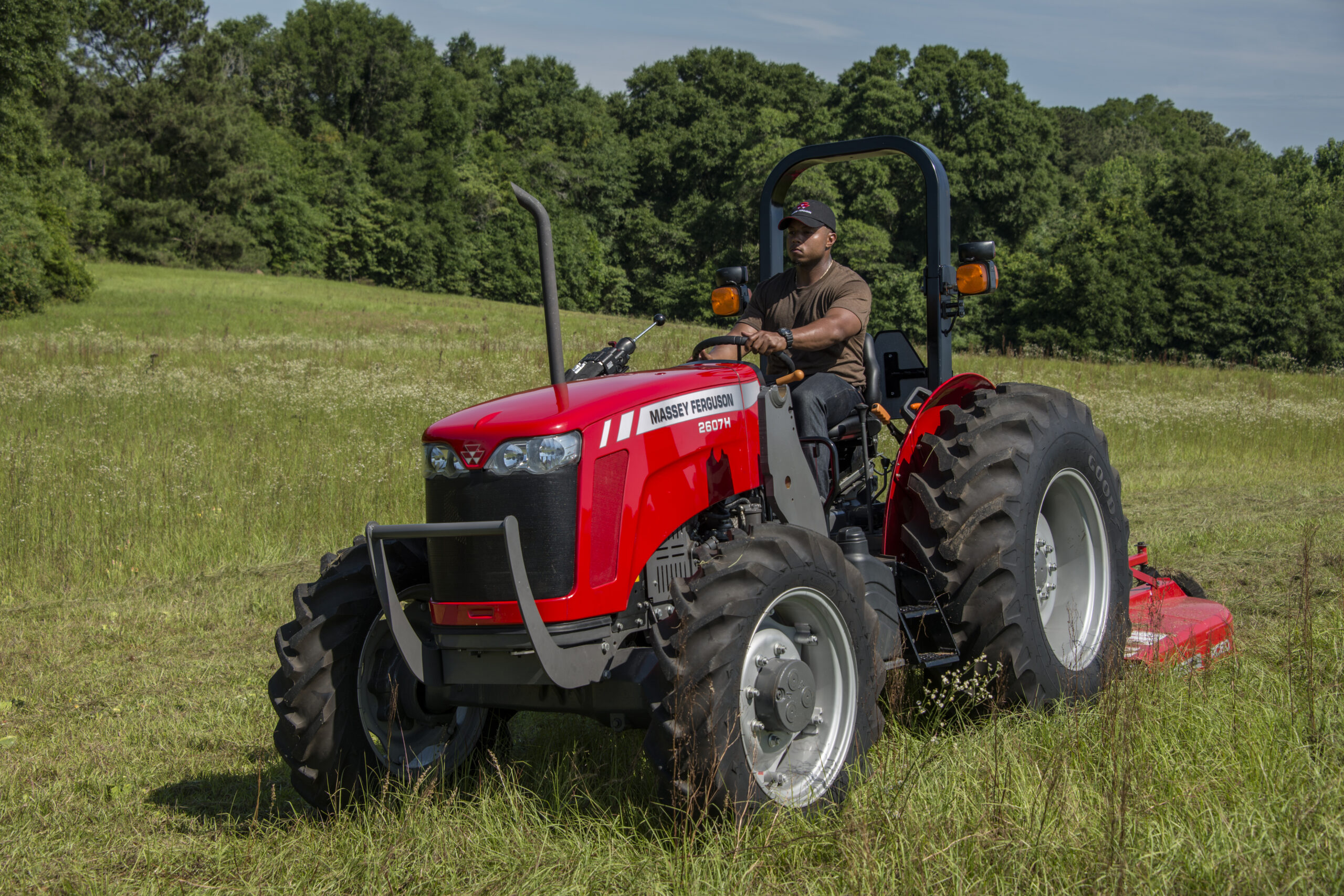 Operator mowing field with a Massey Ferguson 2600H utility tractor, built for dependable performance in pasture and land management.