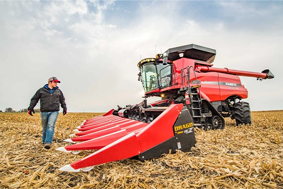 Thumbnail for Farmer standing next to a Case IH 8240 combine equipped with a Drago Series II corn head, ready for high-efficiency corn harvest in a stubble field.