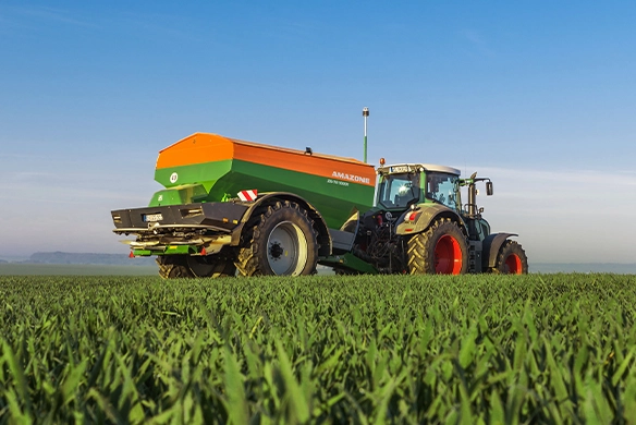 Amazone ZG-TS 10001 spreader paired with a Fendt tractor spreading fertilizer across a lush green field for optimized crop growth.
