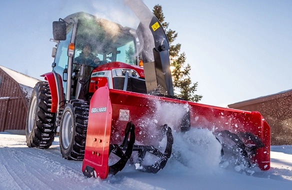 Thumbnail for Massey Ferguson 1M Series compact tractor equipped with a rear snow blower, actively clearing snow on a residential property.