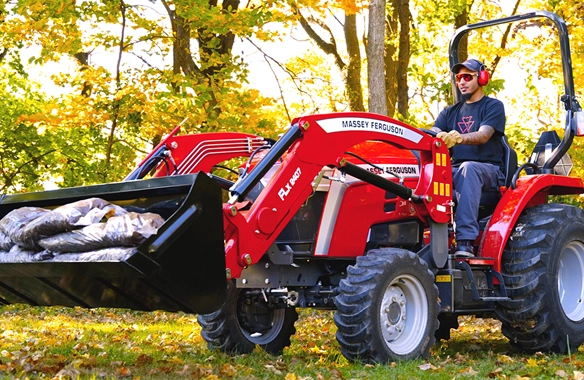 Massey Ferguson 1E Series compact tractor being driven on a dirt path, demonstrating ease of use and comfort in outdoor tasks.