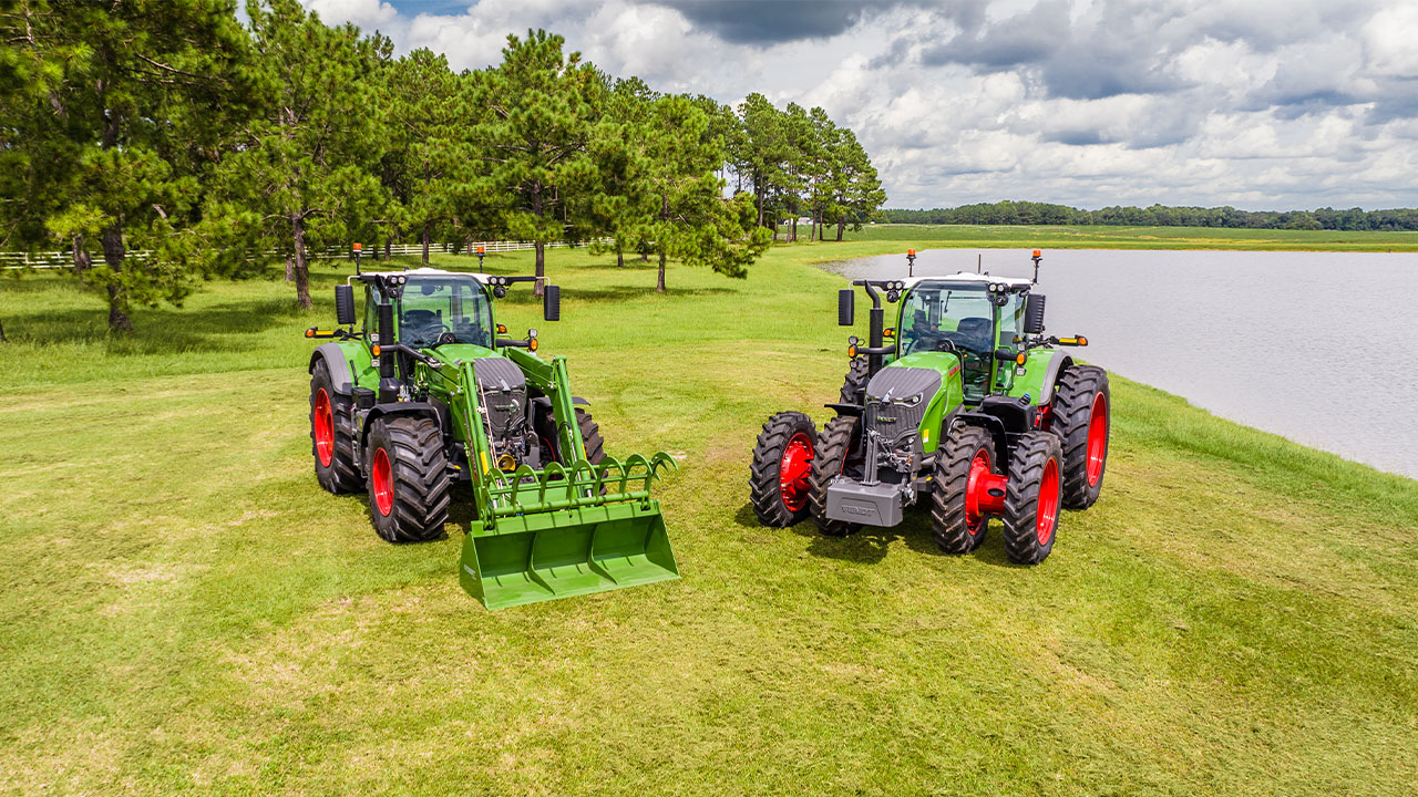 Two Fendt 700 Vario Gen7 tractors parked on grass by a lake, showcasing premium performance.
