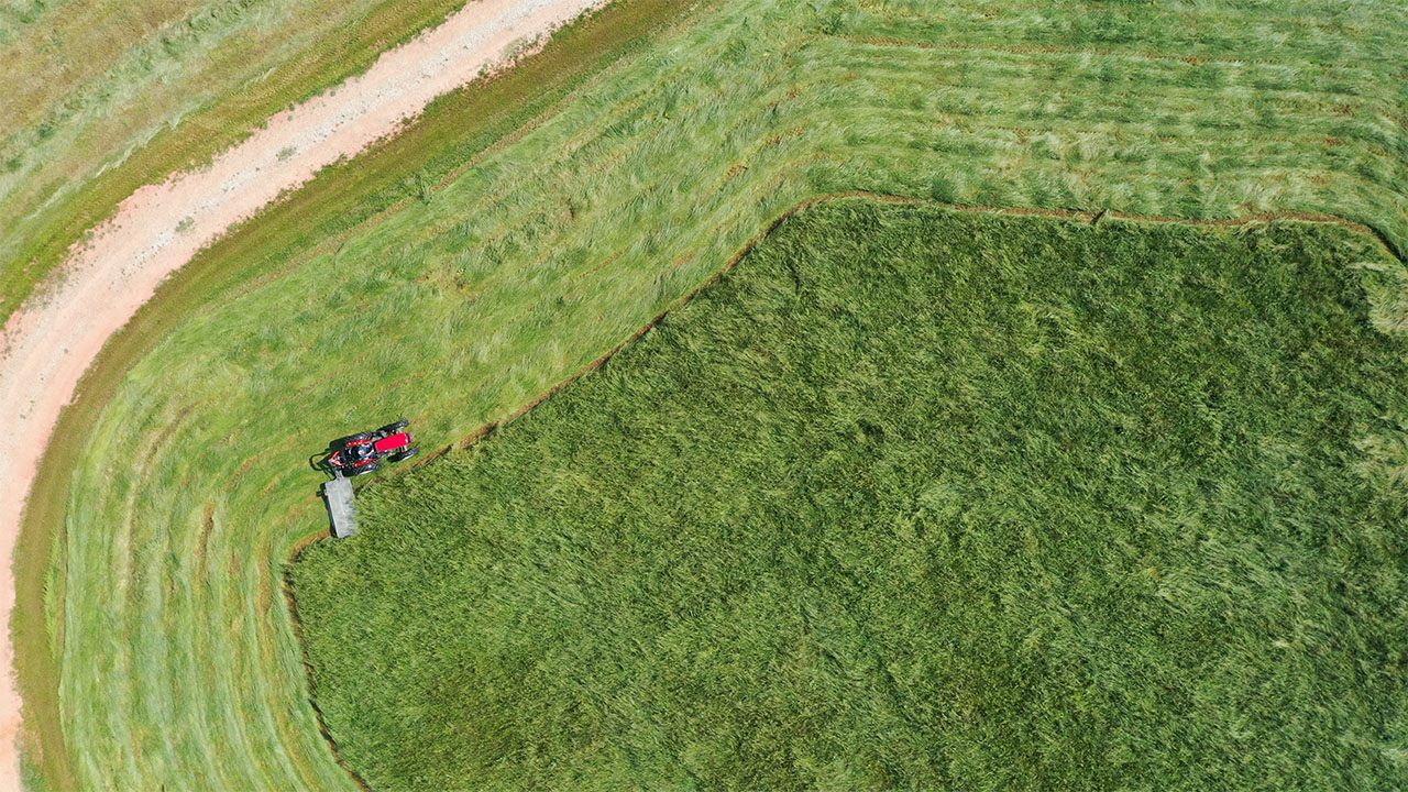 Aerial view of Massey Ferguson tractor with MF DM Series Disc Mower cutting a dense grass field, built for clean, efficient mowing.