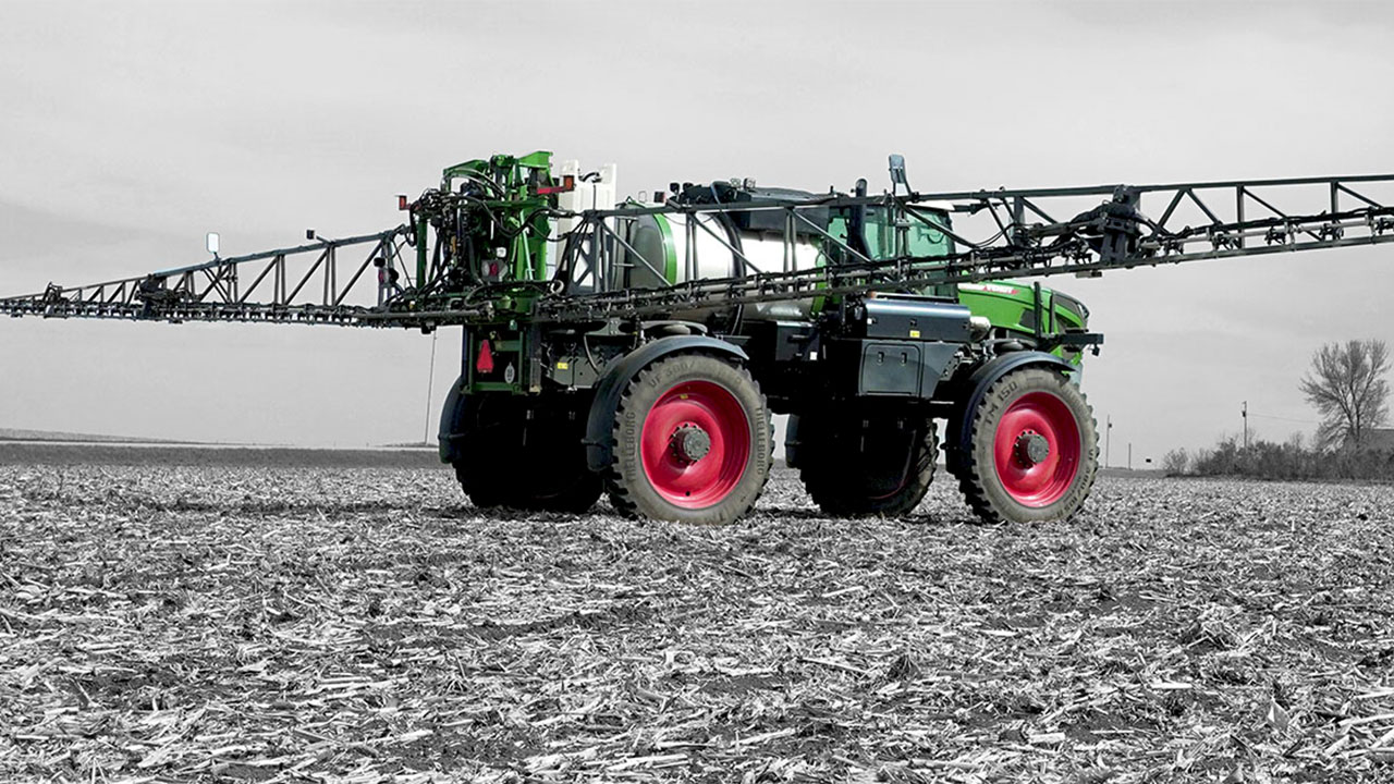 Fendt Rogator sprayer applying crop treatment in a cornfield, precision agriculture, AGCO technology, aerial view.