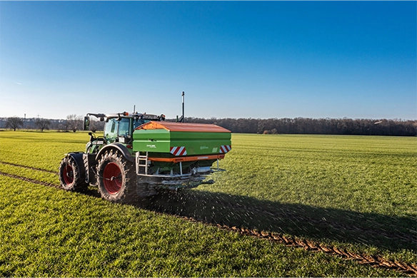 Amazone ZA-TS 4200 with WindControl technology delivering precise fertilizer application in a wide, open grass field using a Fendt tractor.