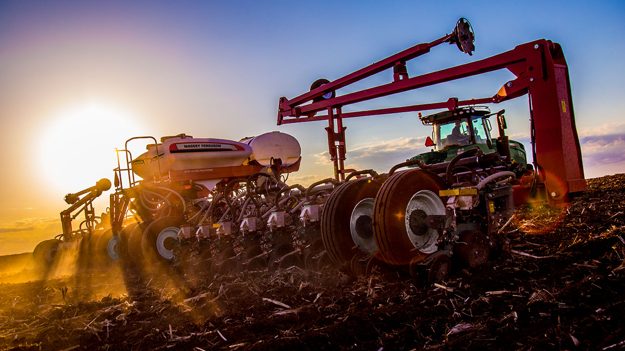 Rear view of a Massey Ferguson planter in action at sunset, planting rows across a field with precision AGCO farming technology.