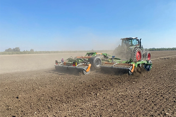 Rear view of Fendt tractor with Amazone Catros+ 9003-2TX in action, demonstrating even soil distribution and robust tillage performance.