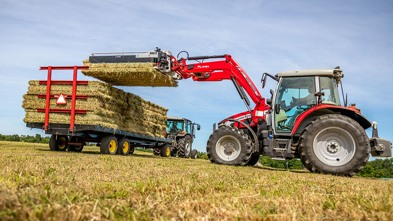 Massey Ferguson 5S Series tractor stacking hay bales on trailer in the field, ideal for efficient hay handling.