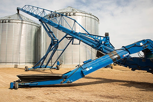 Brandt grain auger near large steel grain bins, designed for high-capacity grain handling.
