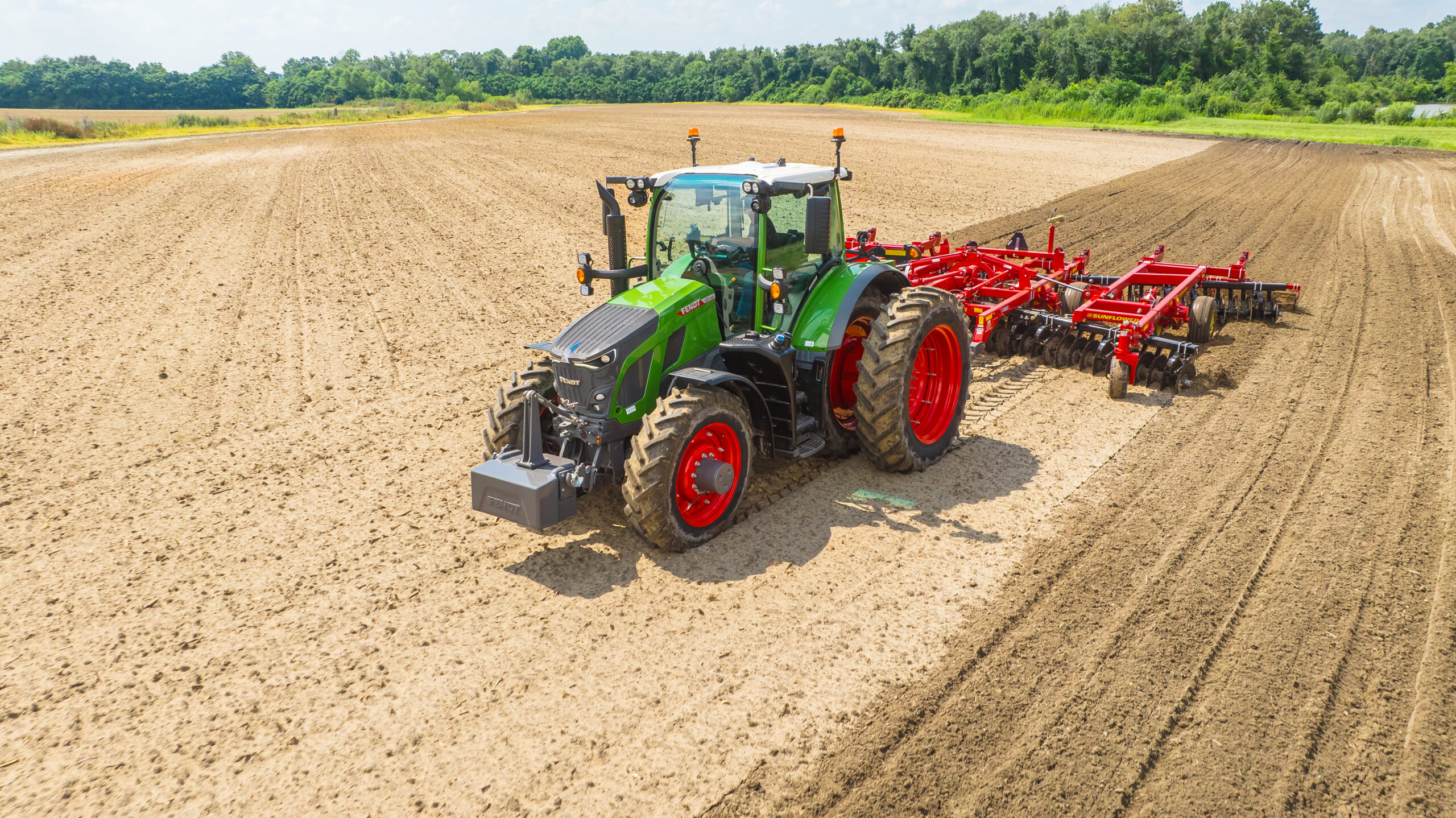 Fendt 600 Vario tractor with Sunflower tillage equipment working a large, open field under sunny skies.