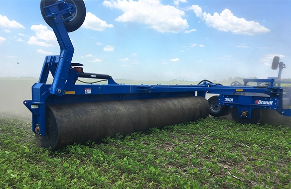 Brandt land roller working in a lush green field, enhancing soil contact and seed germination.