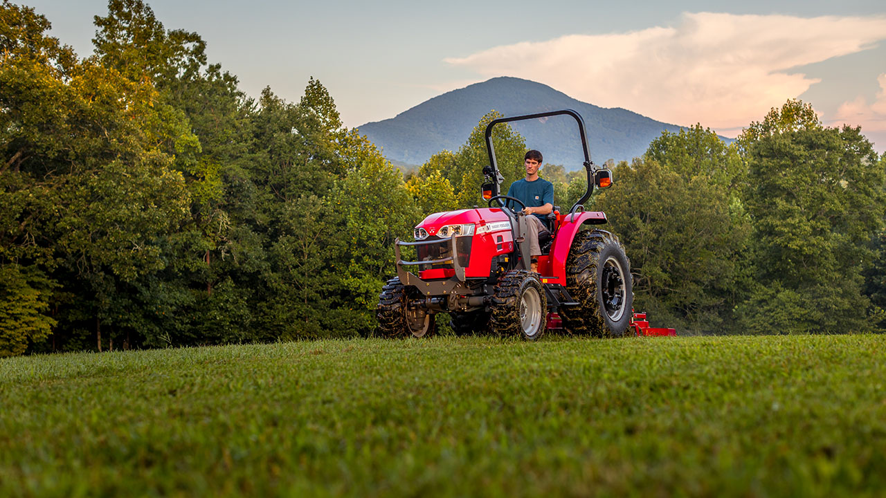 Operator mowing lawn on a Massey Ferguson 1800M compact tractor, ideal for residential and property maintenance tasks.