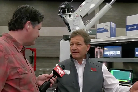 WDRB News reporter interviews an AgRevolution's Stacy Anthony, in front of advanced farm equipment and diagnostic technology at an indoor event.