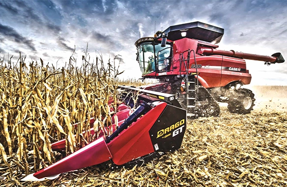 Case IH Axial-Flow combine equipped with a red Drago GT corn head, efficiently harvesting mature corn under dramatic skies.