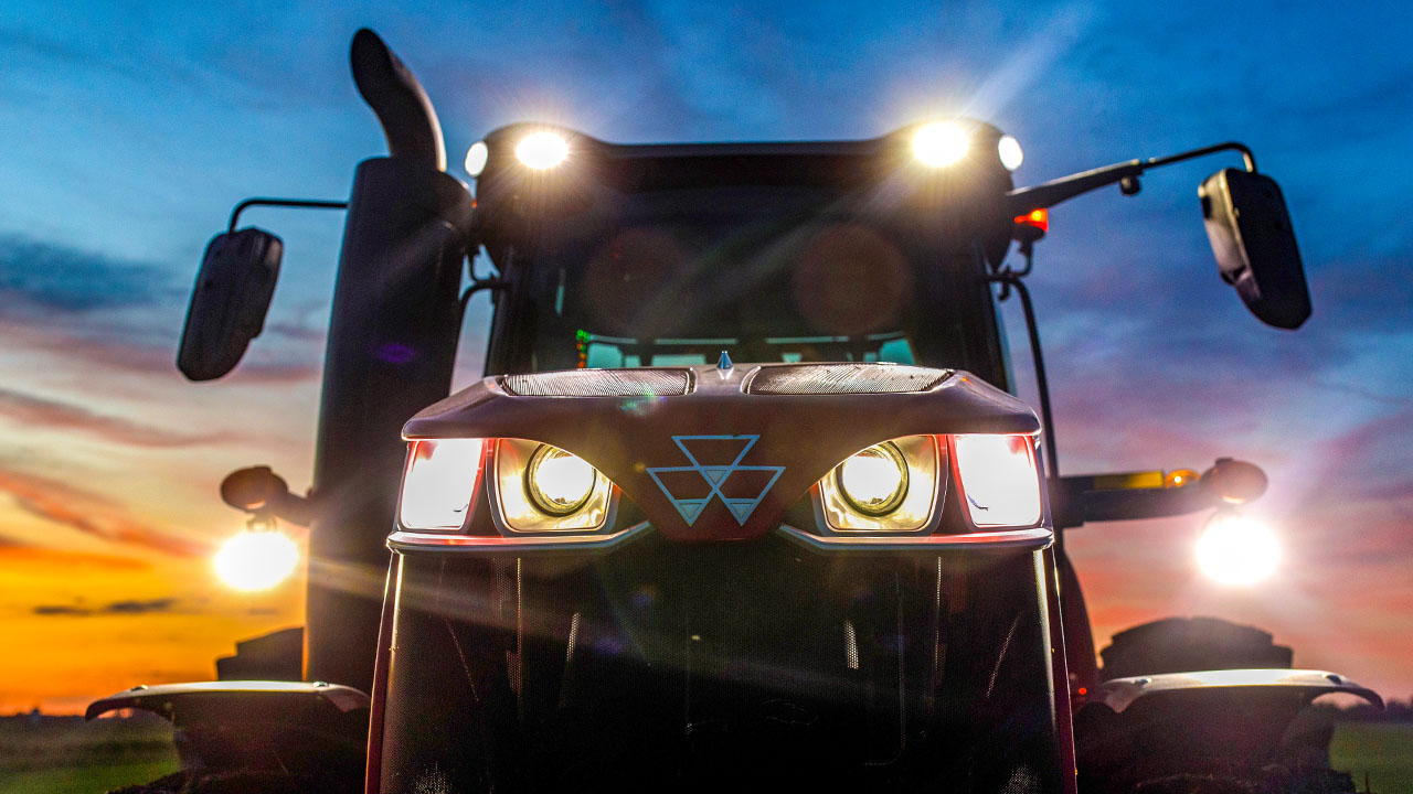 Massey Ferguson 8700 S Series tractor with headlights on at dusk, showcasing power and performance in low-light conditions.