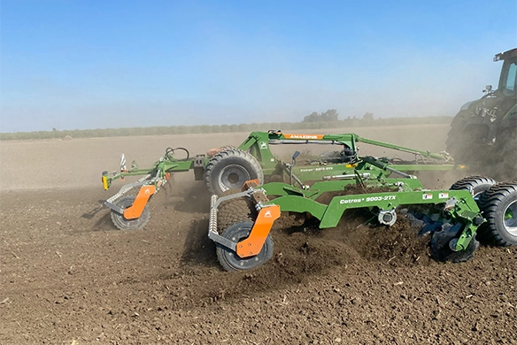 Close-up side view of the Amazone Catros+ 9003-2TX working in the soil, showing aggressive disc action and soil mixing in progress