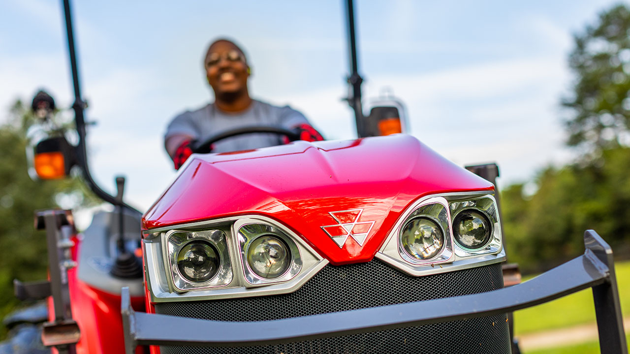 Thumbnail for Close-up of Massey Ferguson 1800M Series tractor front grill and headlights with operator, showcasing bold design and brand identity.
