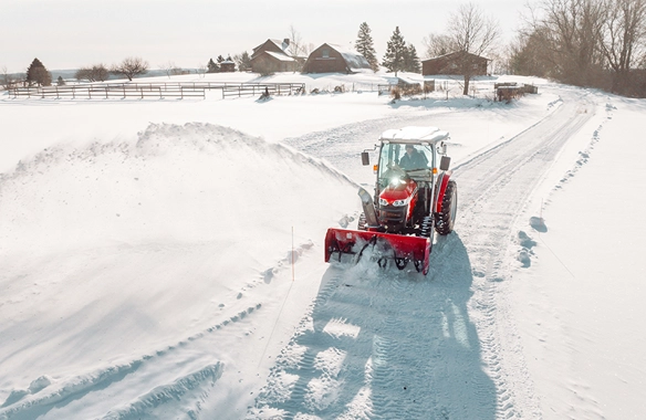 Massey Ferguson 1M Series compact tractor plowing a snow-covered driveway with snow blower attachment, perfect for winter property upkeep.