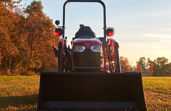 Front-facing view of a Massey Ferguson 1GC Series sub-compact tractor equipped with a front loader, ready for light-duty tasks on a fall morning.