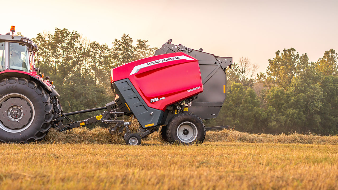 Hesston by Massey Ferguson 1 Series round baler operating in the field with tractor during early morning harvest.