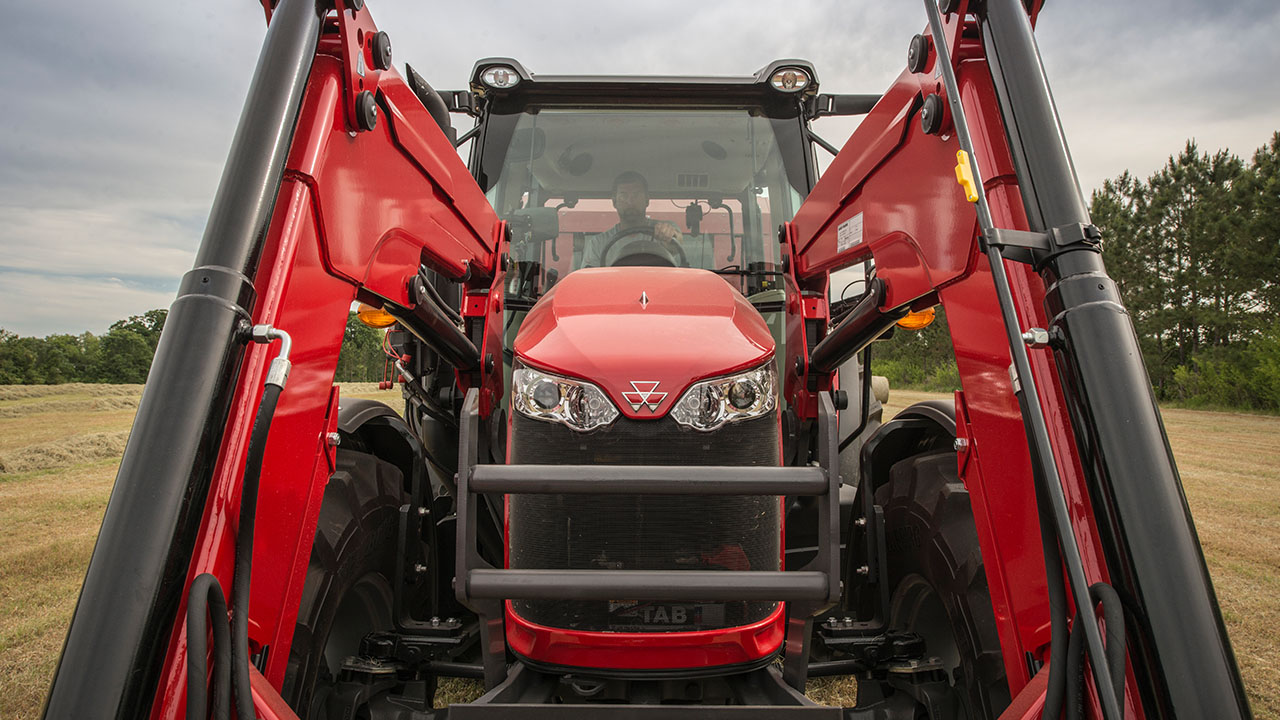 Close-up front view of Massey Ferguson 6700 Series tractor with loader, highlighting rugged build and iconic red design for heavy-duty farming.